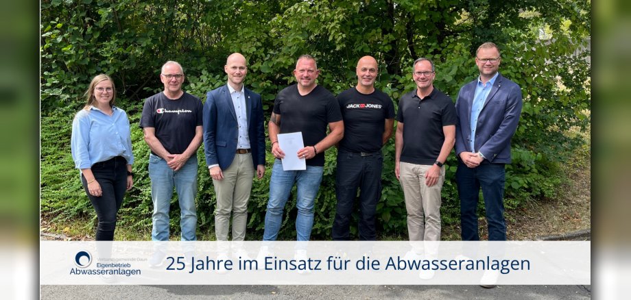 Sieben Personen vor grüner Hecke