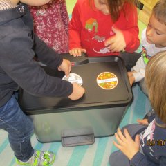 Kinder bekleben einen Mülleimer