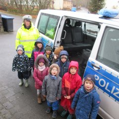 Kindergartenkinder neben Polizeiauto