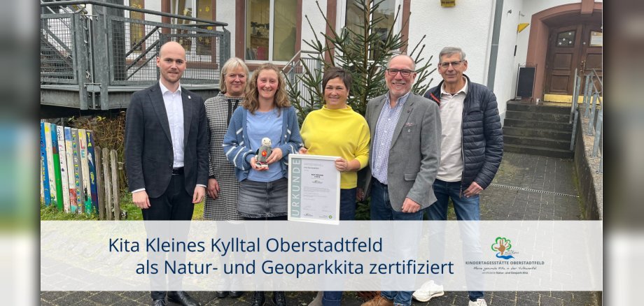 Sechs Personen mit Urkunde vor Kitagebäude