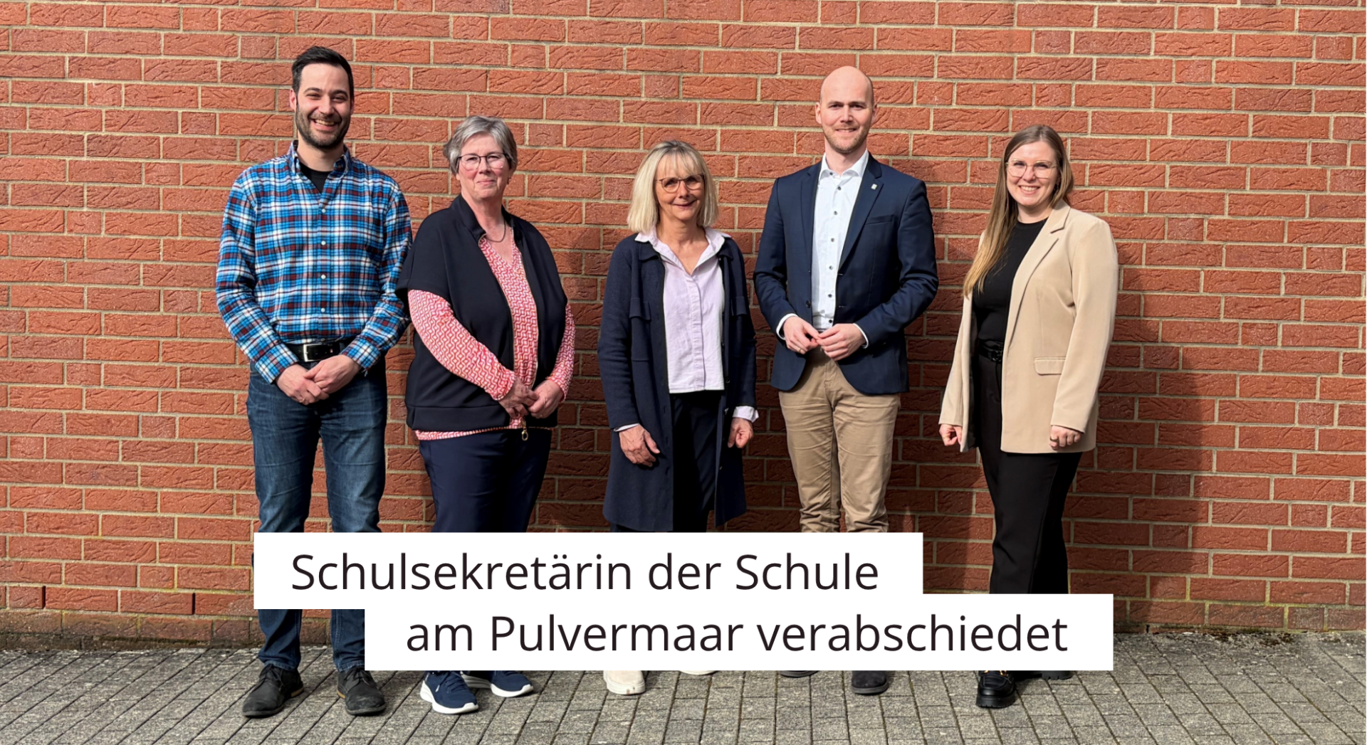 Fünf Personen vor Schulgebäude