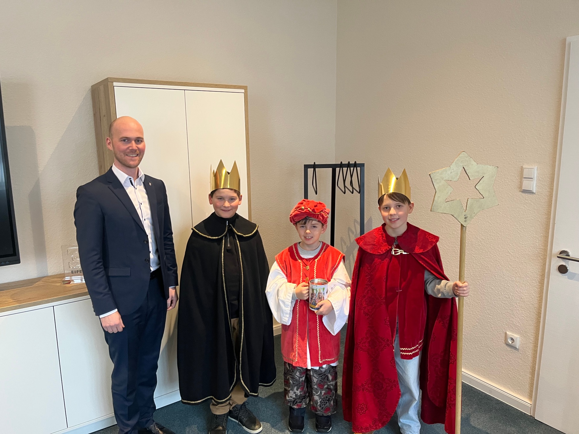 Vier Personen, dabei symbolisieren drei die Sternsinger