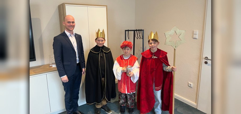 Vier Personen, dabei symbolisieren drei die Sternsinger