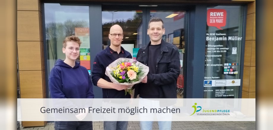 Drei Personen, in der Mitte mit Blumenstrauß