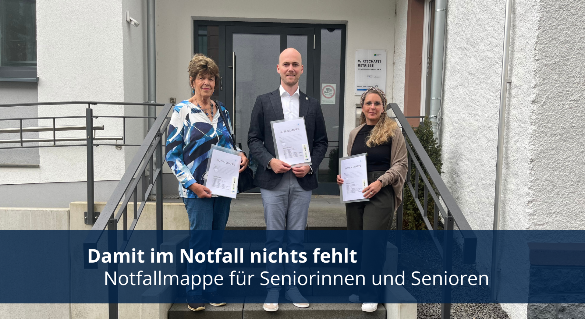 Drei Personen mit Mappen in den Händen vor Verwaltungsgebäude