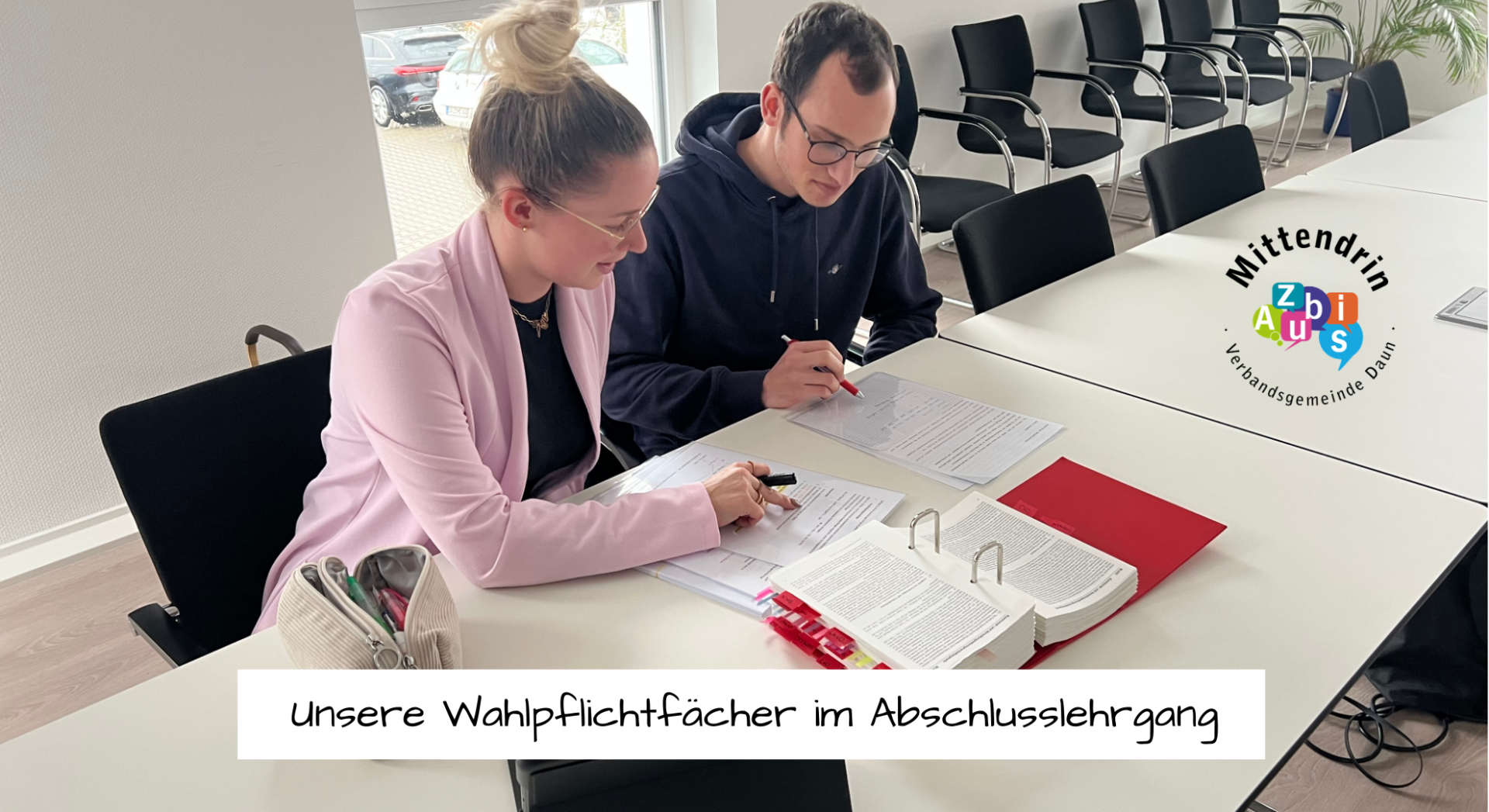 Zwei Auszubildende sitzen am Tisch mit Lernunterlagen