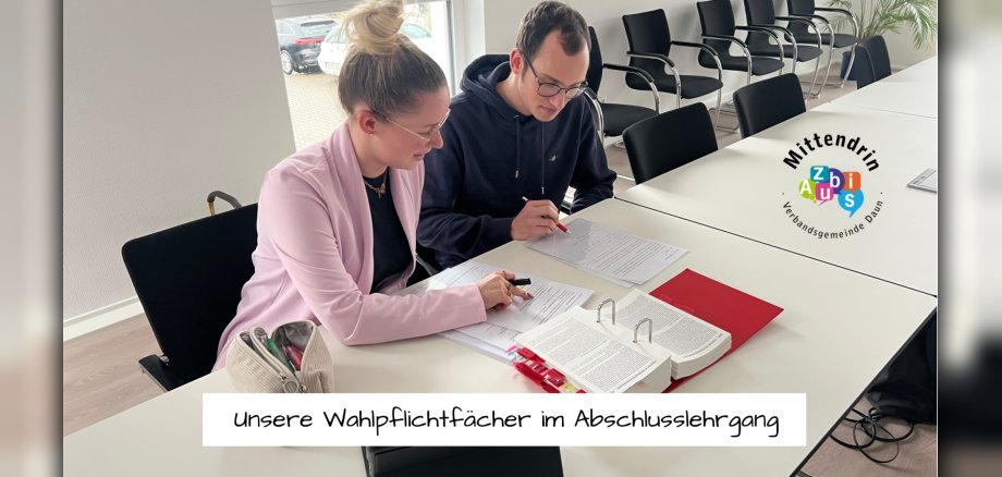 Zwei Auszubildende sitzen am Tisch mit Lernunterlagen